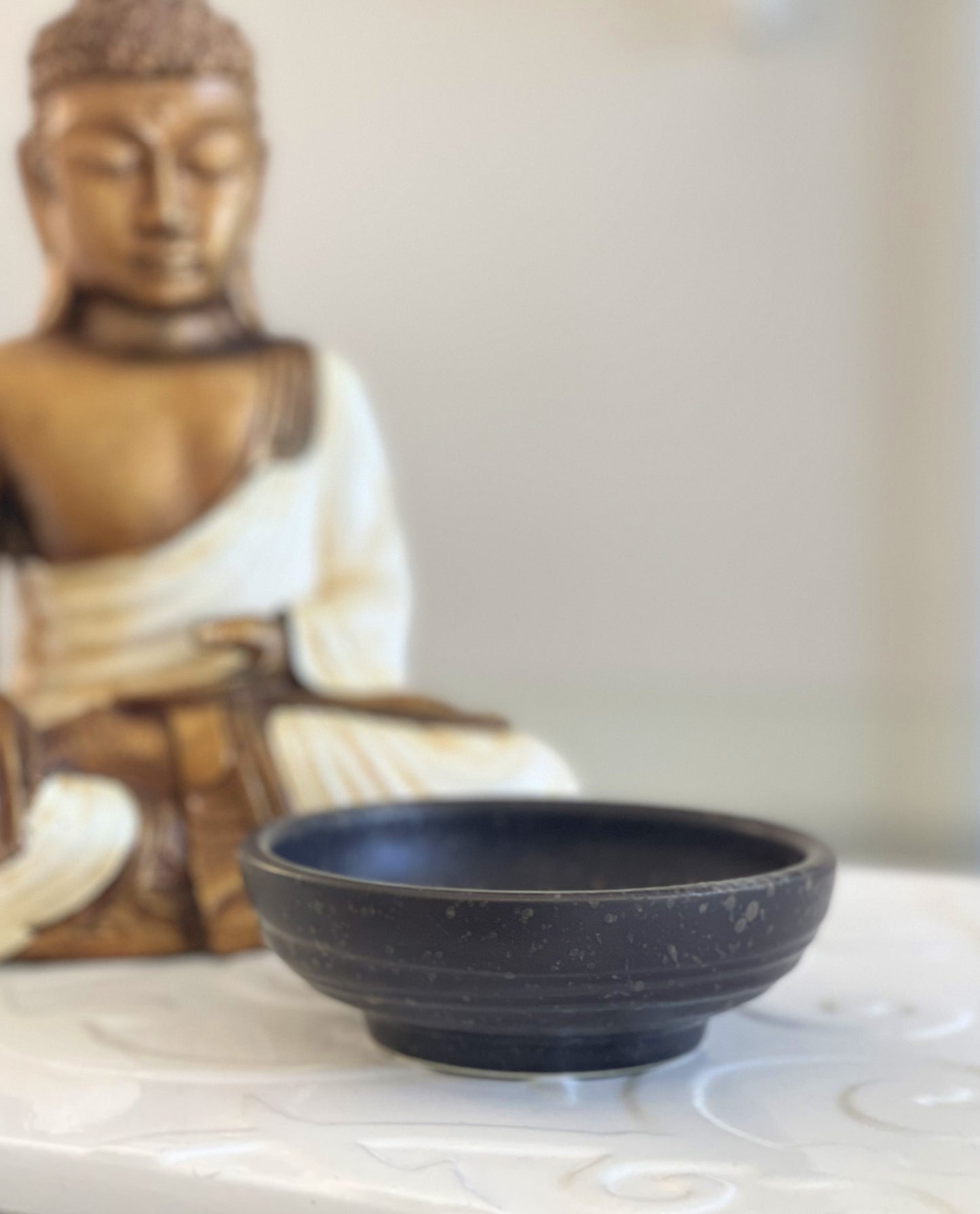 A brown speckled ceramic smudging bowl and a ceramic Buddha.